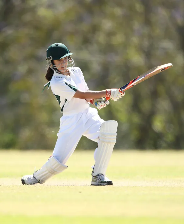 Woman batting in cricket match.